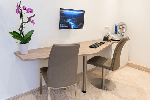 Modernes, helles Büro mit zwei Stühlen, Holzschreibtisch, Monitor und Orchidee.